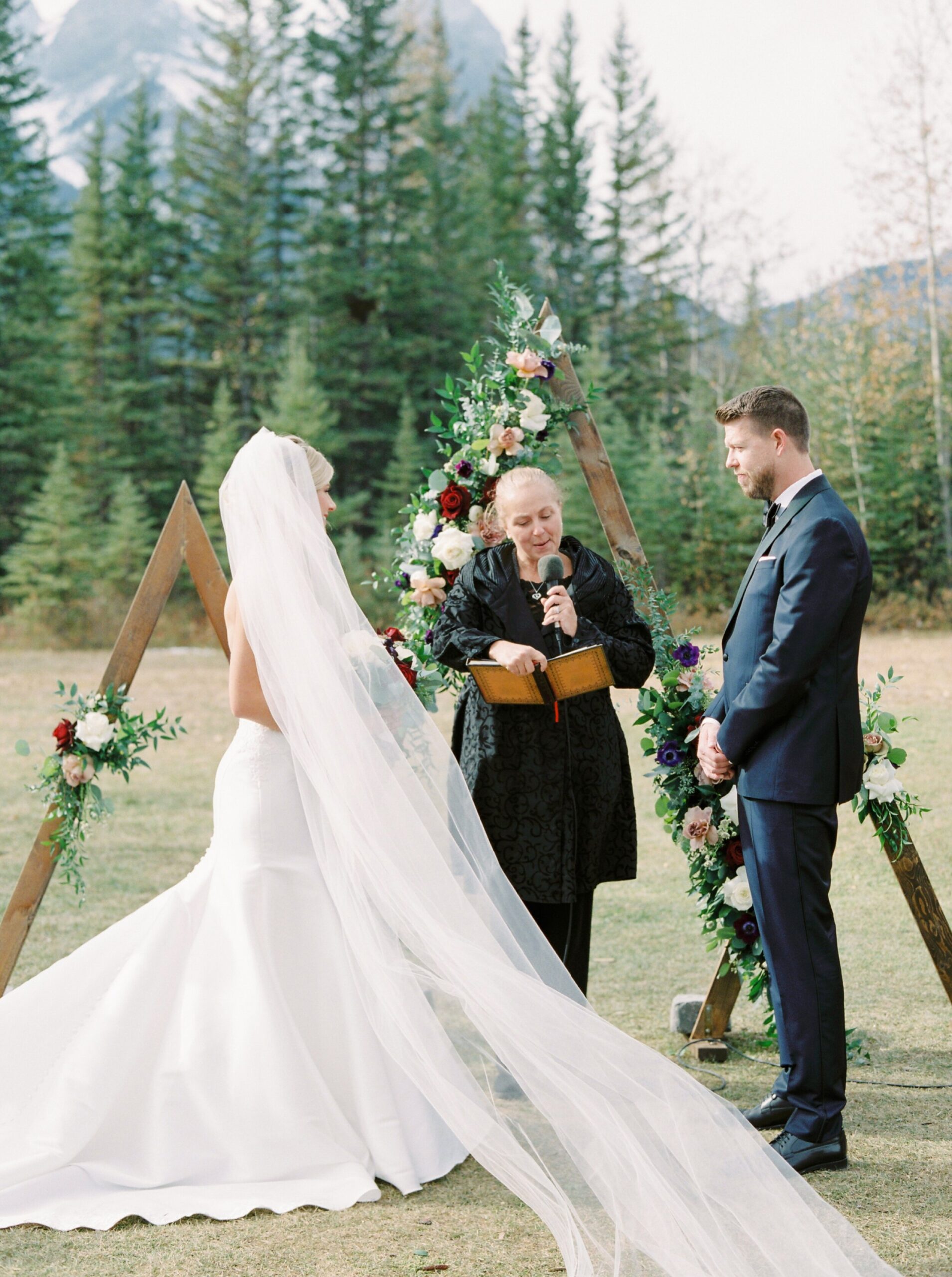  Outdoor mountain ceremony with a triangle floral arch | Cornerstone Theater & Canmore Ranch Wedding Photographers 