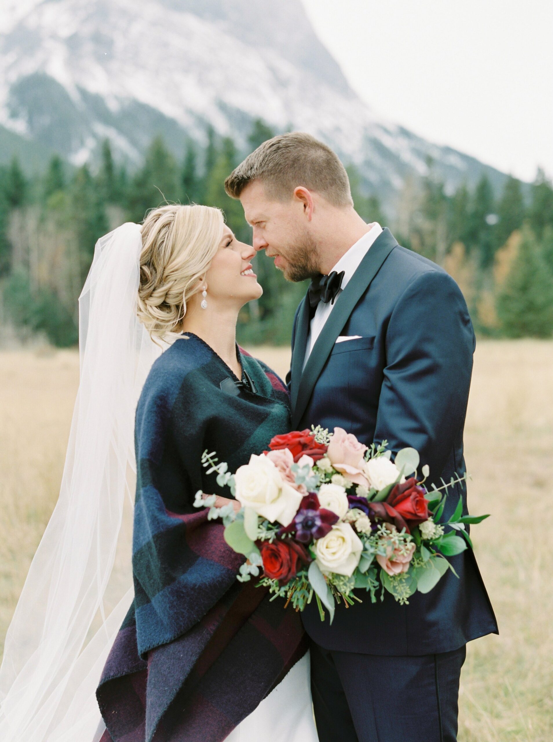  bride keeping warm in plaid shawl for winter wedding in the mountains | Cornerstone Theater & Canmore Ranch Wedding Photographers 