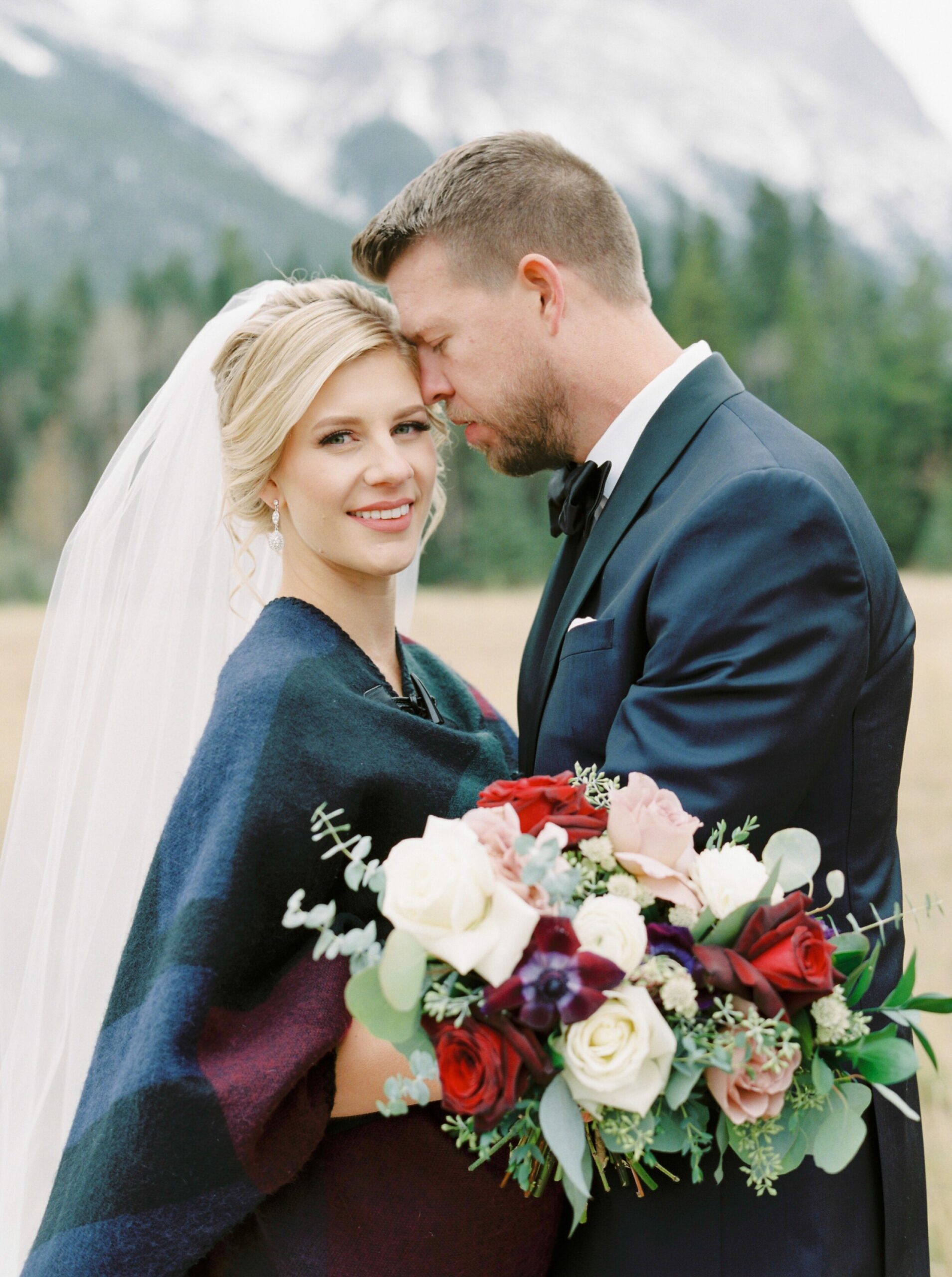  bride keeping warm in plaid shawl for winter wedding in the mountains | Cornerstone Theater & Canmore Ranch Wedding Photographers 