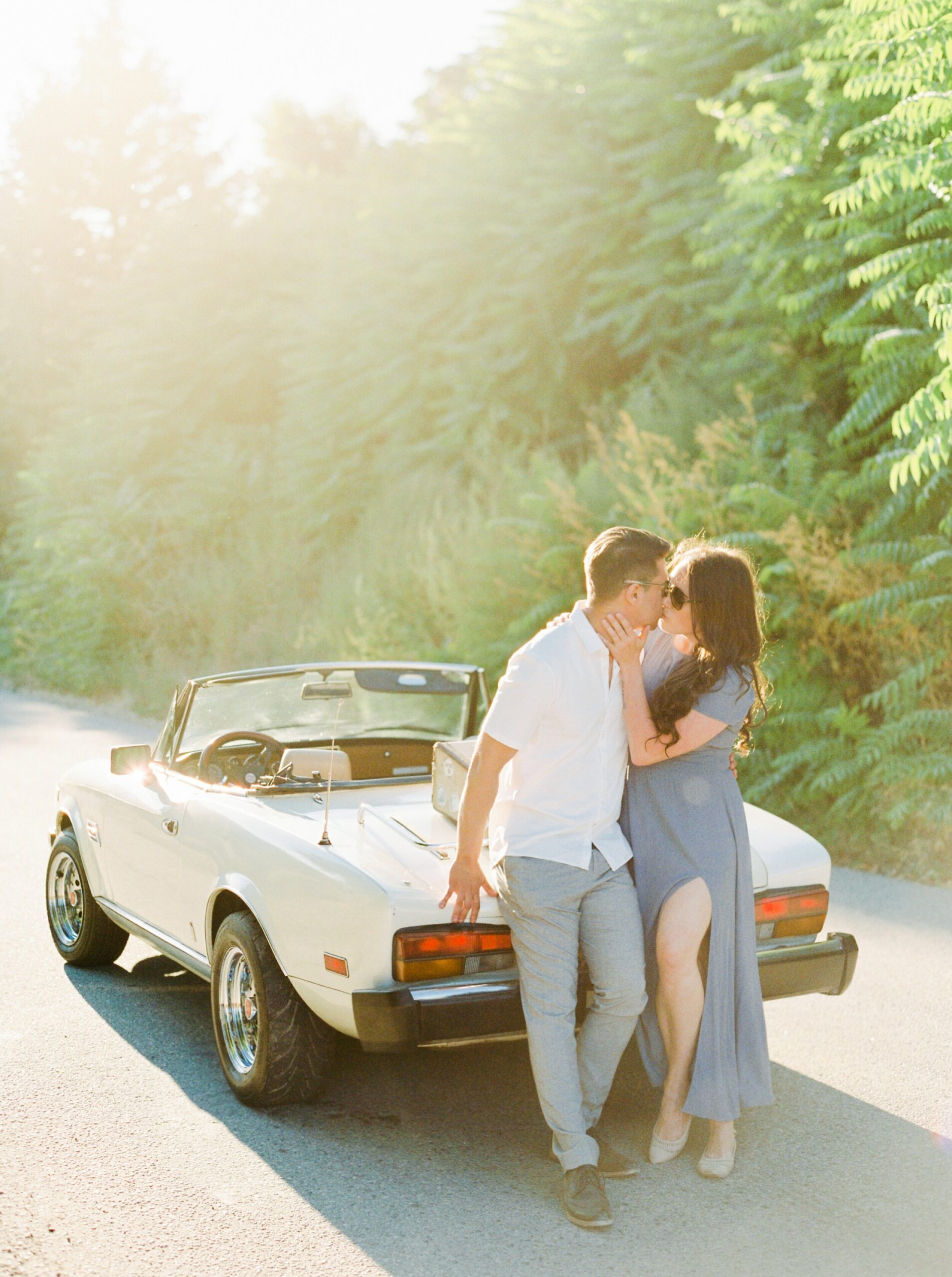  vintage white car and suitcase for a fun road trip in kelowna okanagan penticton vineyard on the naramata bench | summer engagement session | outfit ideas for couples photos | film photographer Jusitne Milton 