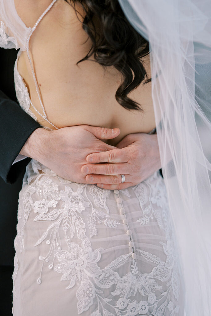 couples wedding portait, groom's hands around brides waist by wedding photographer in Banff Canada. 