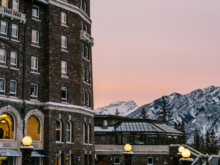 Sunset creates beautiful pink sky against Banff Spings Hotel and  mountain peaks in Banff, Canada