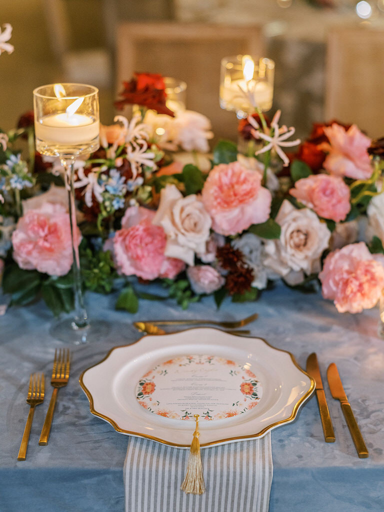 wedding reception table settings featuring candles, florals, and place settings in the color pallet of blue and gold with pink, white and red accent at Banff Springs Hotel 