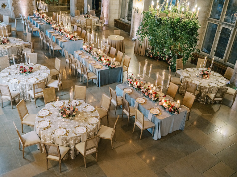 wedding reception design settings featuring long tables, chandeliers with greenery, candles, florals, and place settings in the color pallet of blue and gold with pink, white and red accent at Banff Springs Hotel 