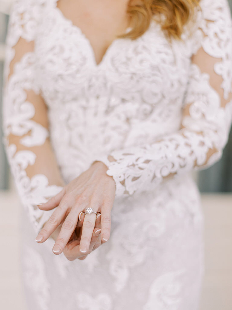 beautiful bride shows wedding ring while earing long sleeved wedding dress. 
