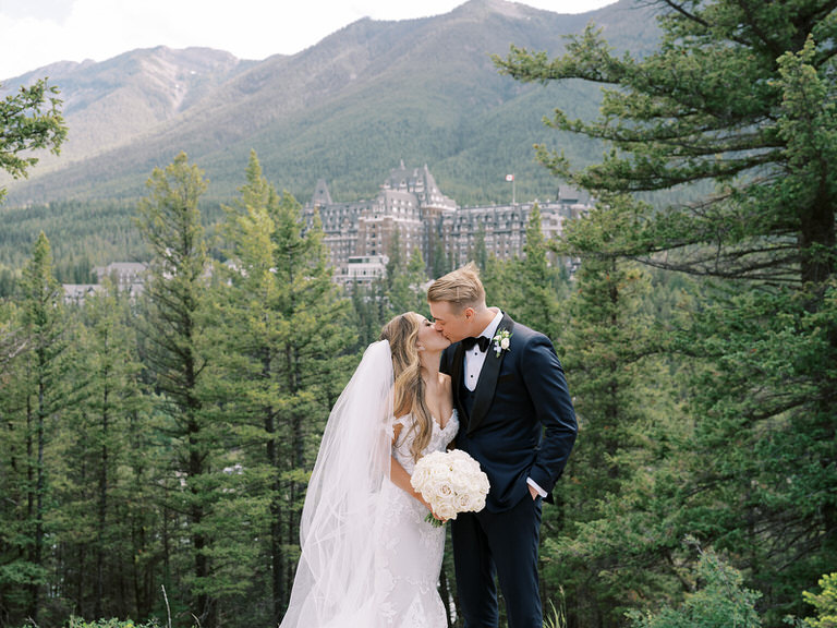 Bride and Groom wedding portrait in Canadian Rockies with mountains, forest and iconic Fairmont Banff Spings Hotel