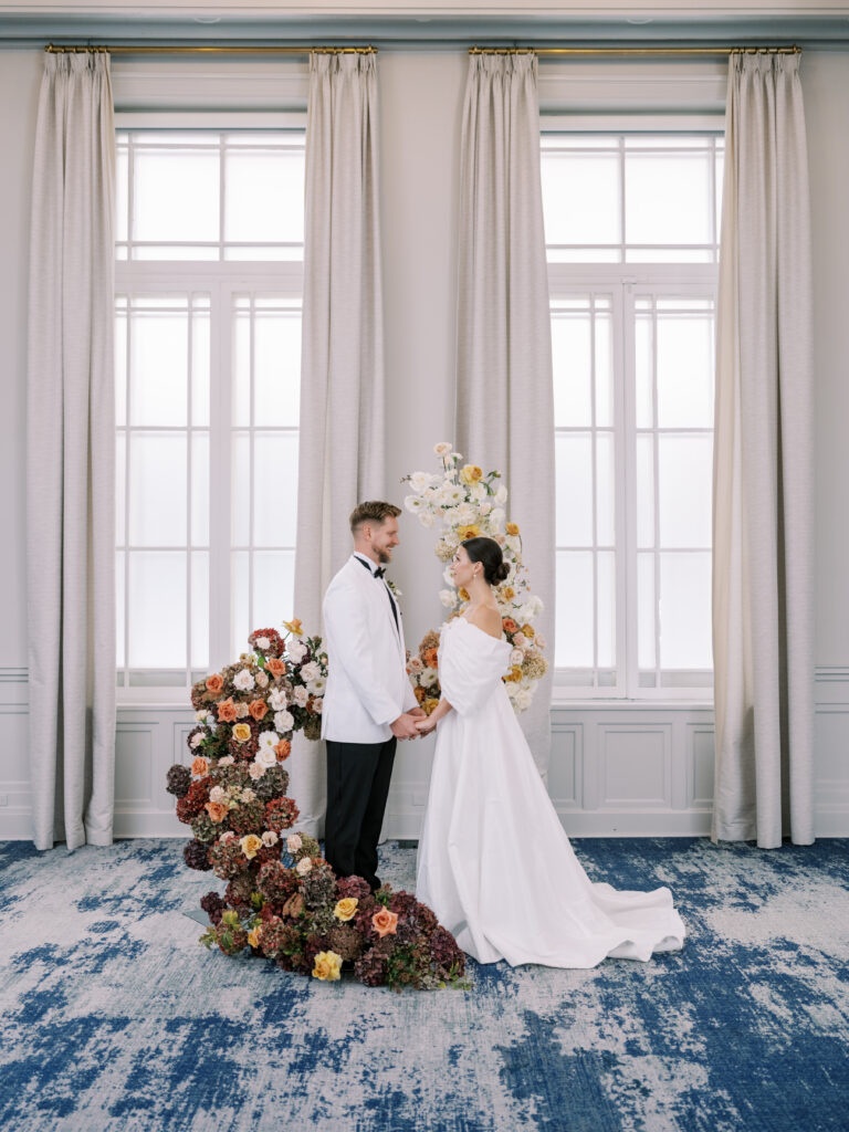 bride and groom during wedding ceremony wrapped by a cascading floral arch