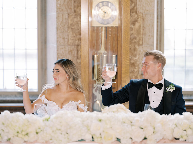 Bride and groom at head table giving a toast during wedding speeches