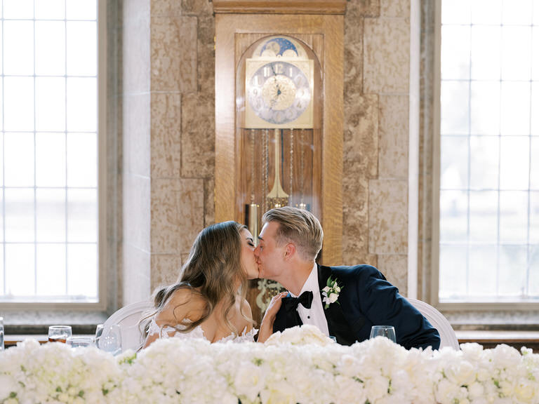 Bride and groom at head table kissing during wedding speeches