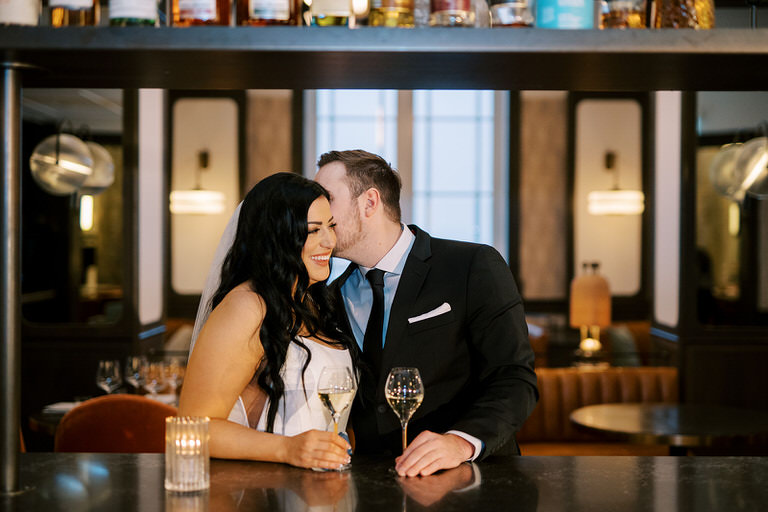 Modern bride and groom celebrate their wedding day with cocktails at a bar in Calgary, Alberta. 