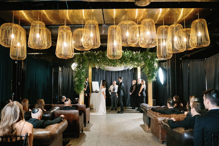 ceremony space for the kiddushin with green foliage, gold and black accents