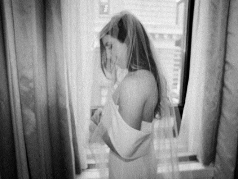 Bride in wedding dress and veil before Bedeken, black and white, editorial wedding photography style