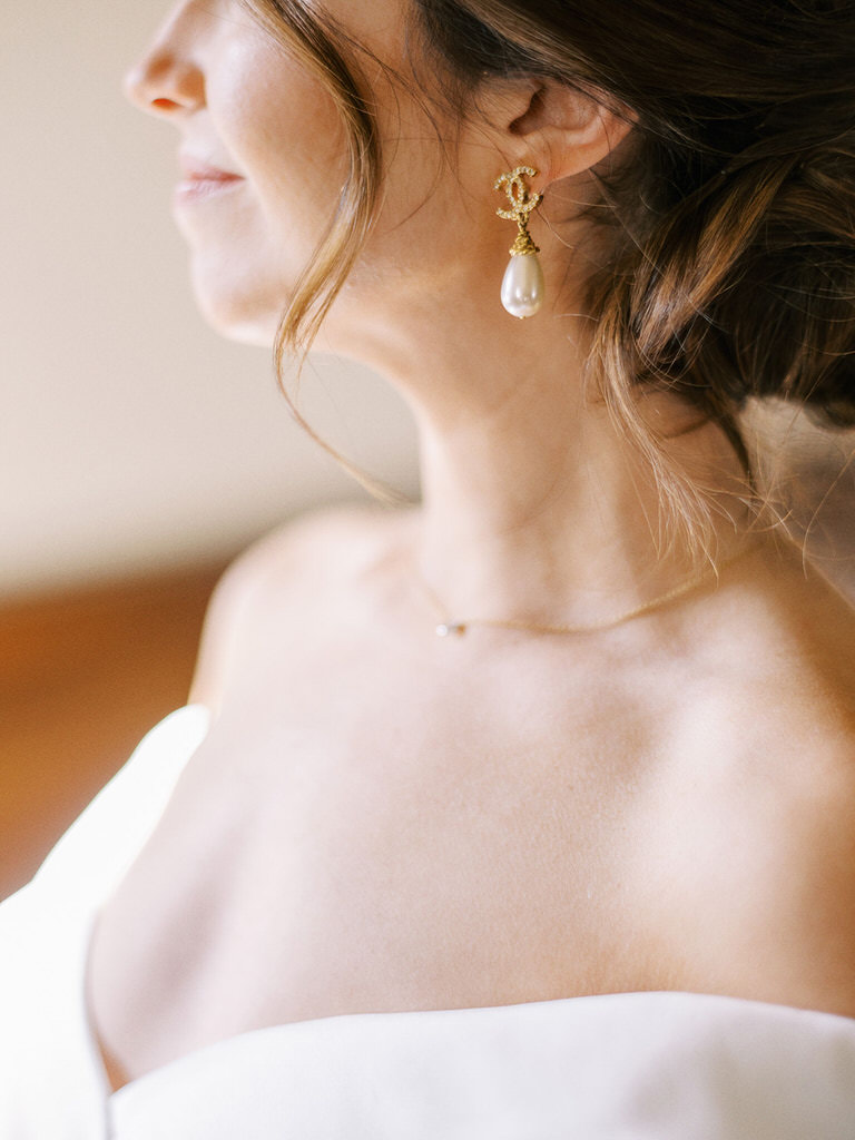 CLose up of bride details featuring pearl earrings and strapless dress