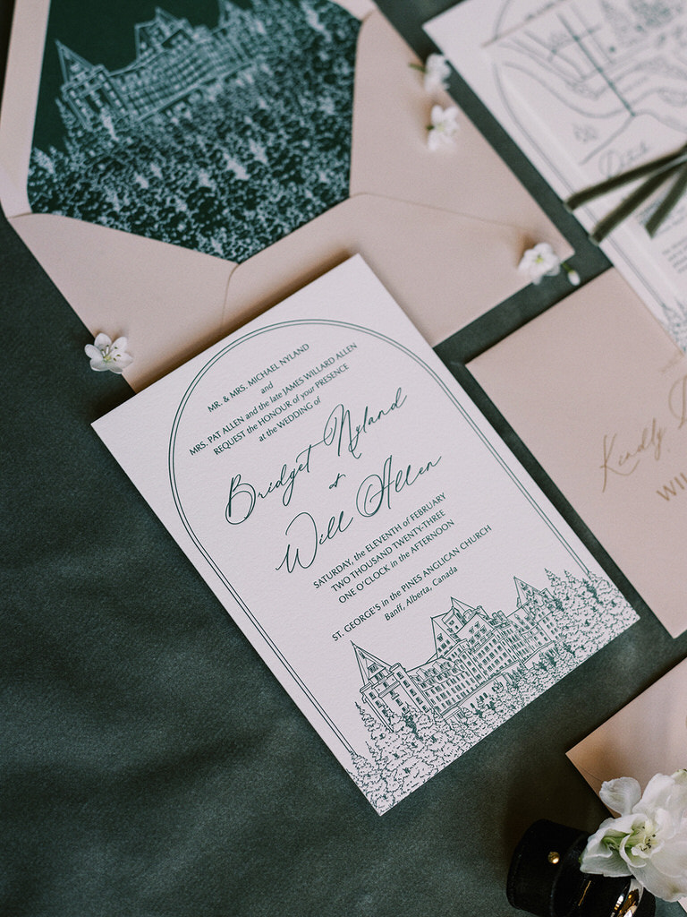wedding flatlay featuring details of the wedding stationary with dark green, pearls, and white florals.  