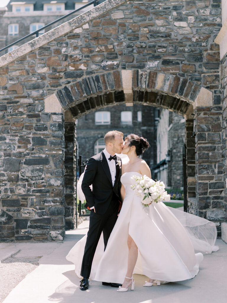Bride and Groom couples portrait, pearl trend heels, strapless dress, white florals bouquet, black tux, couple kissing. 