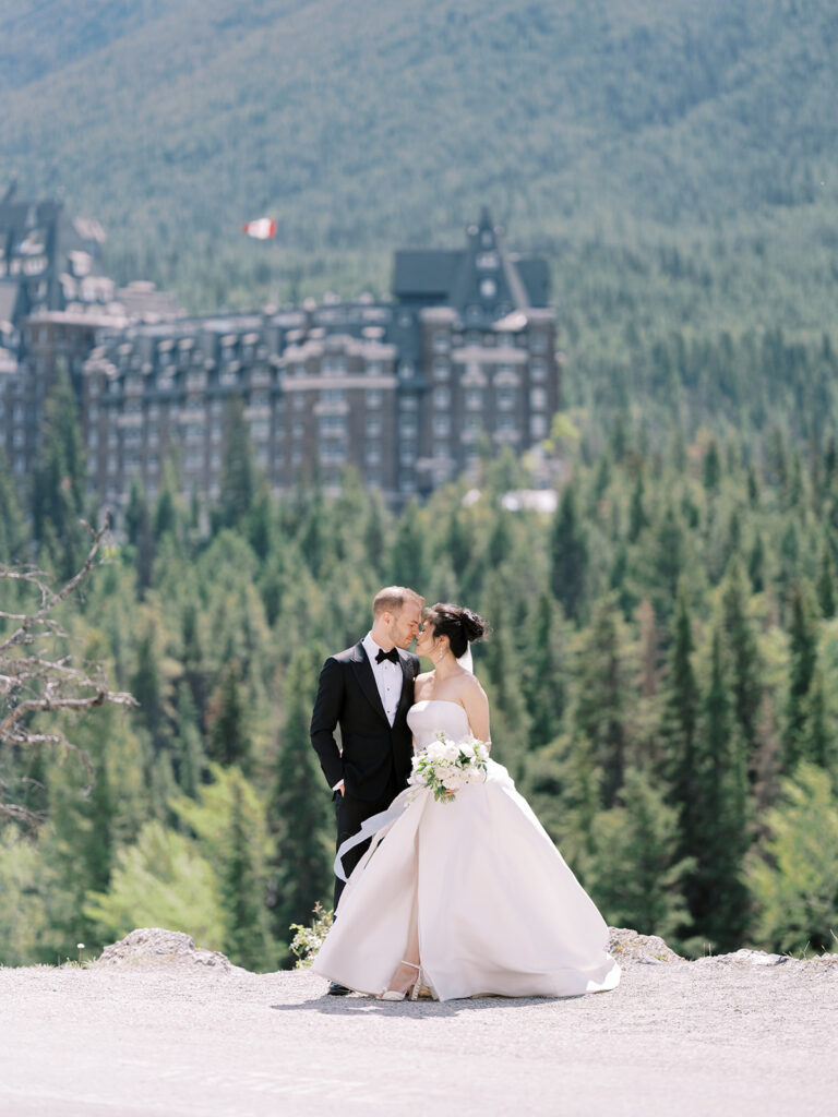 Bride and Groom couples portrait, white floral bouquet, mountain wedding photography Banff Springs Fairmont Hotel in the background. 