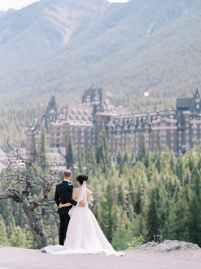 Bride and Groom couples portrait, white floral bouquet, mountain wedding photography Banff Springs Fairmont Hotel in the background. 