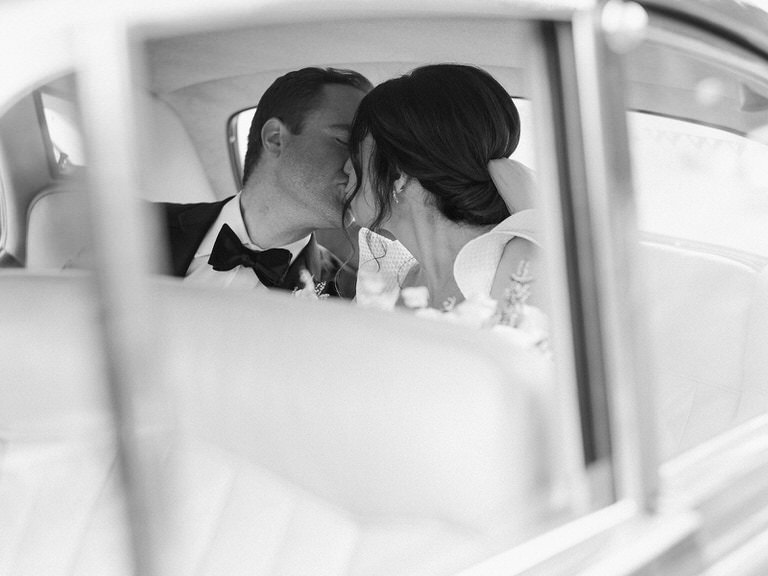 black and white photography. bride and groom couples portrait, with vintage car and mountain background. 