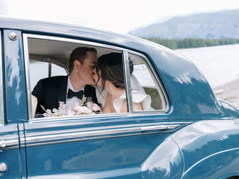 fine art photography. bride and groom couples portrait, with vintage car and mountain background. 