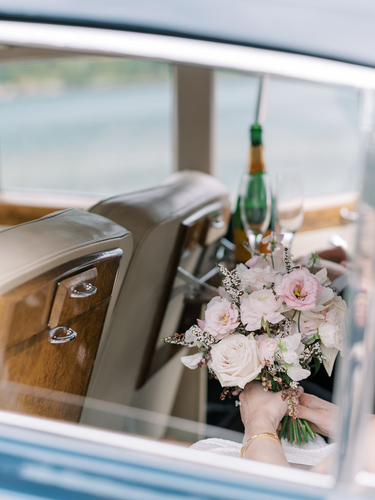 fine art photography. bride and groom couples portrait, with detail shot of  back seat of vintage car with champaigne bottle, glasses. wedding florals of light pink and white.  Mountain background. 