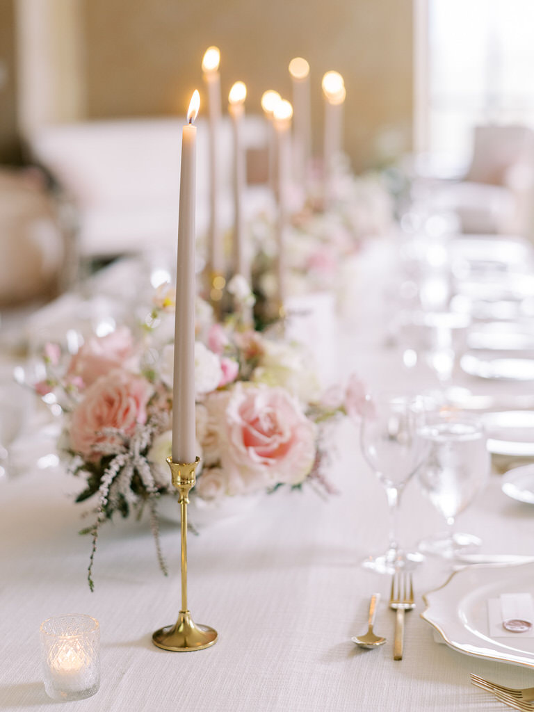 wedding reception space in Fairmont Banff Springs hotel. Light pink pastel and white florals, gold features, white linens, and long candles accent wedding table. 