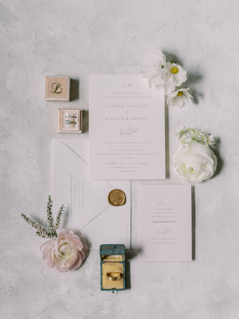 Bridal flatlay with wedding details, including  blush pink and white florals, wedding stationary from Plush Invites, and personalized ring box with bride's initials