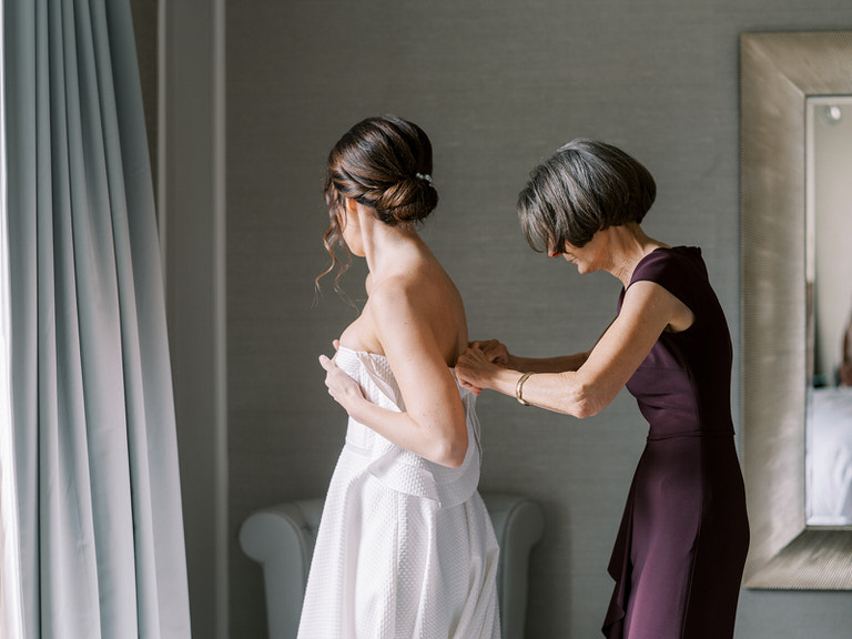 bridal getting ready portrait - mother of bride helping to do up wedding dress