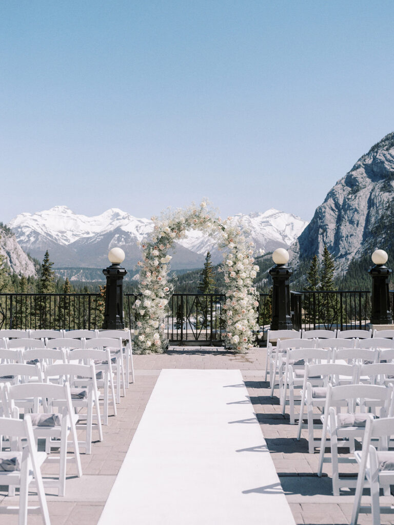 Fairmont Banff Springs Hotel wedding ceremony on the terrace with stunning modern babys breath and roses arch captured by Banff wedding photographer Justine Milton