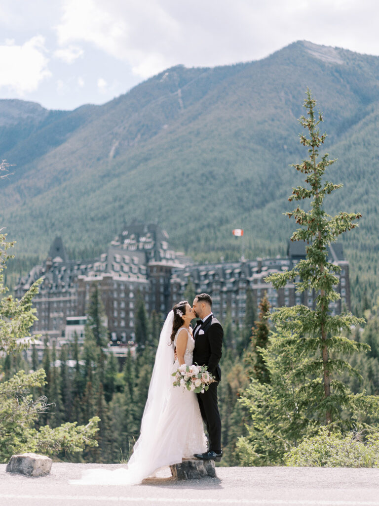 film Banff photographer captures bride and groom kissing in front of the stunning Castle in the rockies, the Fairmont Banff Springs
