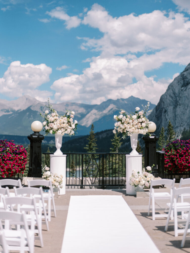 Fairmont Banff Springs Hotel Terrace ceremony decor. Large urns overflowing with white and blush florals captured by Banff Wedding Photographer Justine Milton