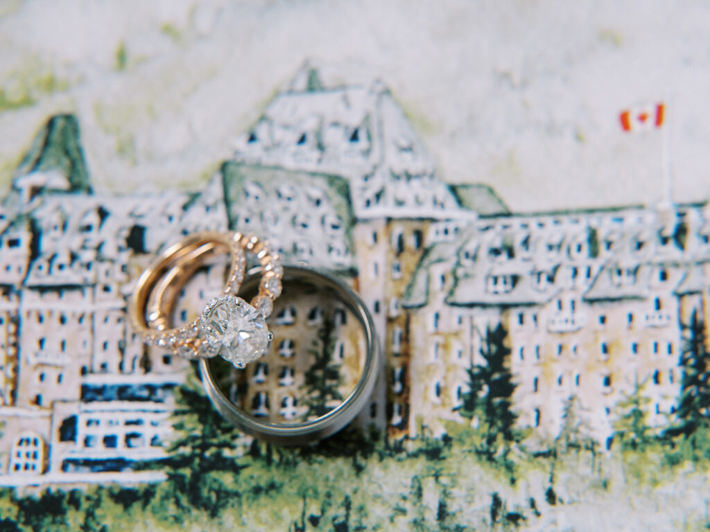 watercolor painting of the Fairmont Banff Springs Hotel with oval cut diamond engagement ring captured by Banff Wedding Photographer Justine Milton