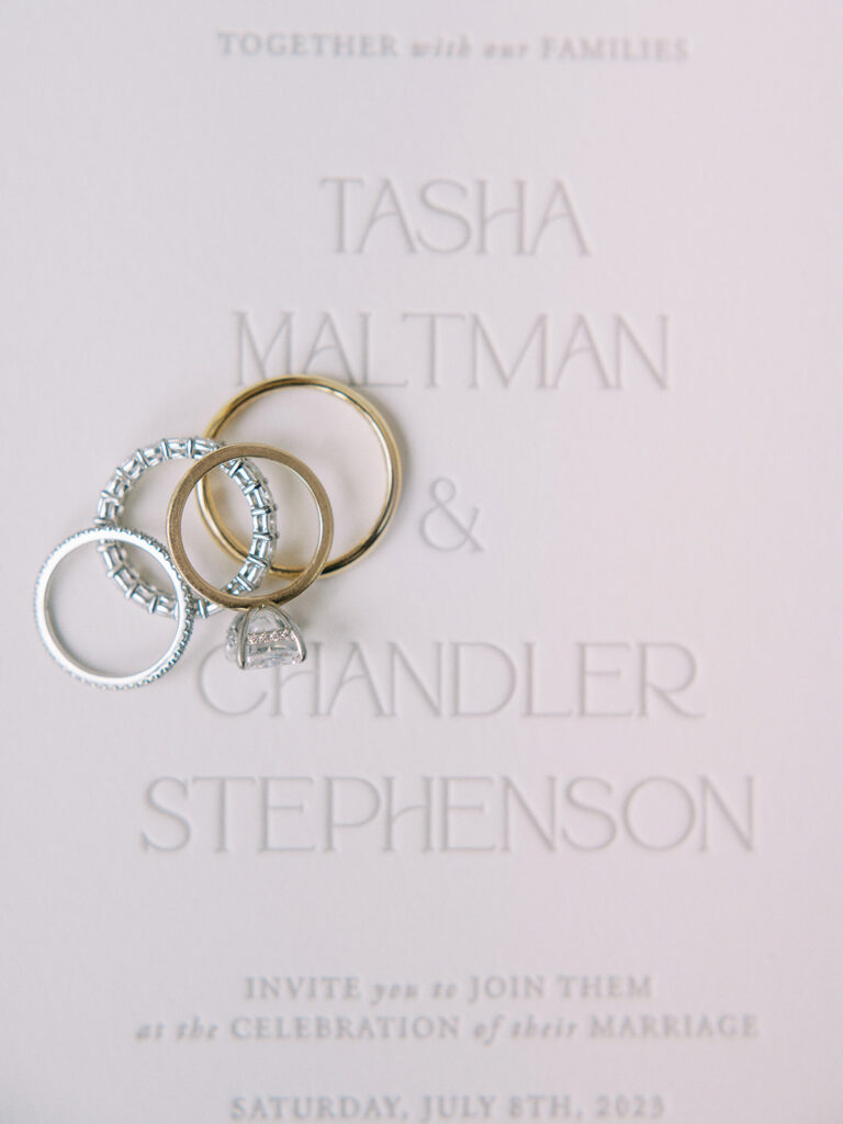 oval cut diamond engagement ring and wedding bands on the invitation for tasha and chandler stephenson captured by Canadian and destination wedding photographer Justine Milton