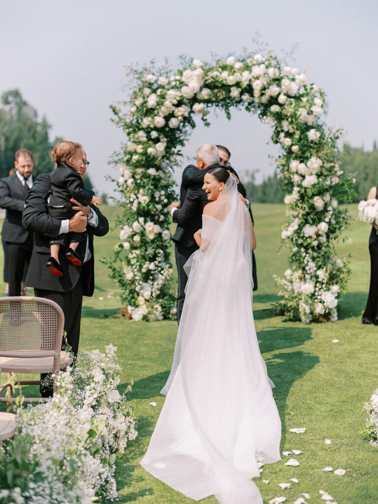 cute candid moment where the bride is laughing with her son at the front of the ceremony aisle at Elk Ridge resort for the wedding of tasha and chandler stephenson captured by Canadian and destination wedding photographer Justine Milton