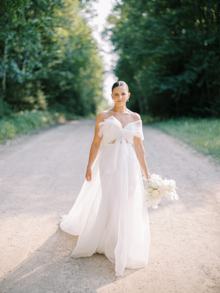 Chich fashionable bride Tasha Stephenson in Newhite wedding dress with a bow in front at Elk Ridge Resort captured by Canadian and destination wedding photographer Justine Milton